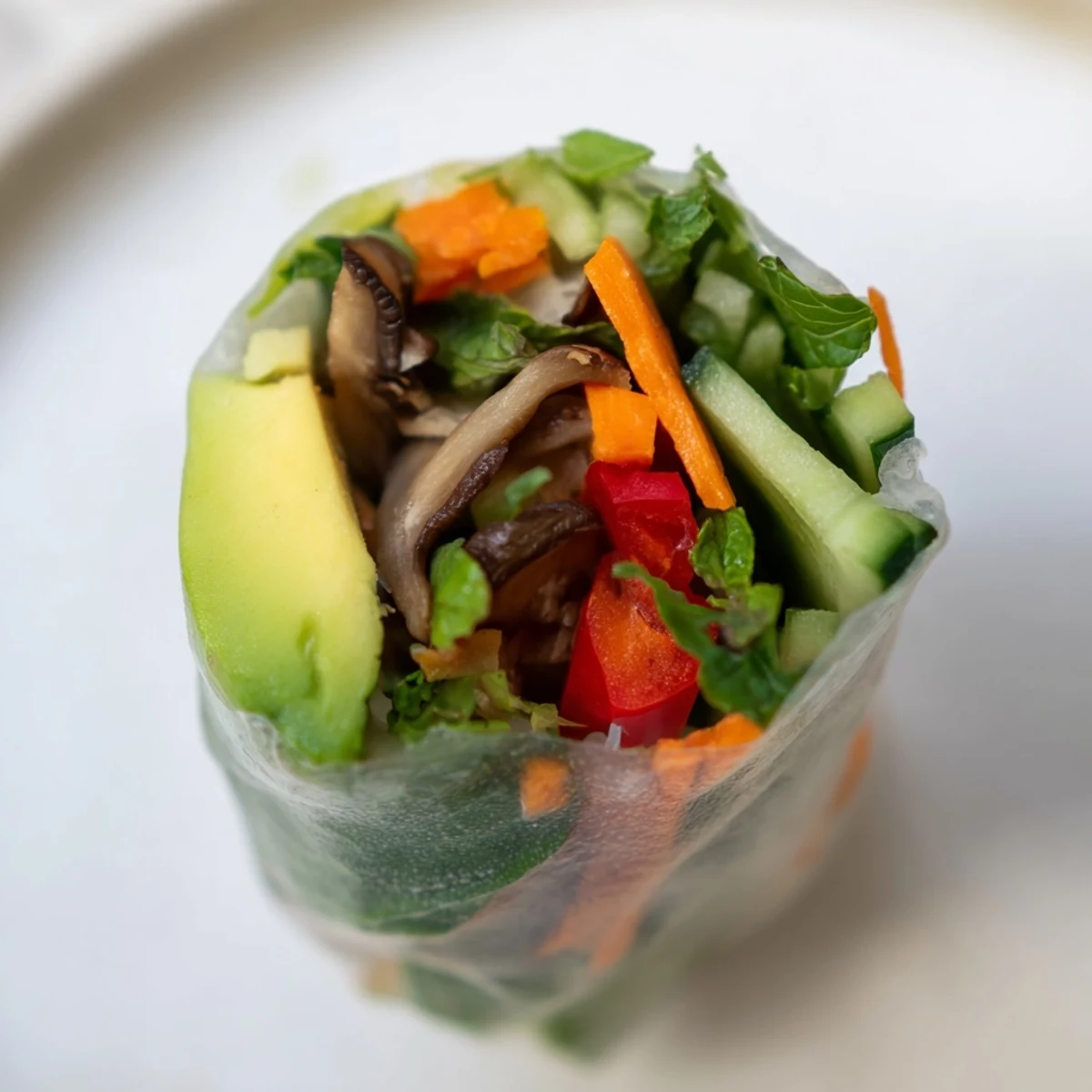 Creamy avocado shiitake spring rolls wrapped in translucent rice paper with fresh herbs and crisp vegetables