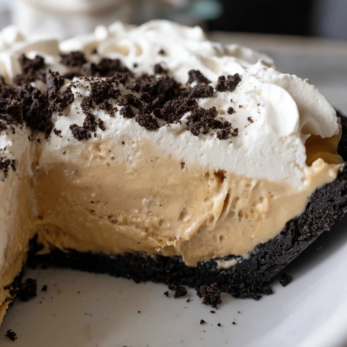 Silky peanut butter Oreo pie slice revealing the chocolate crust and fluffy whipped cream garnish