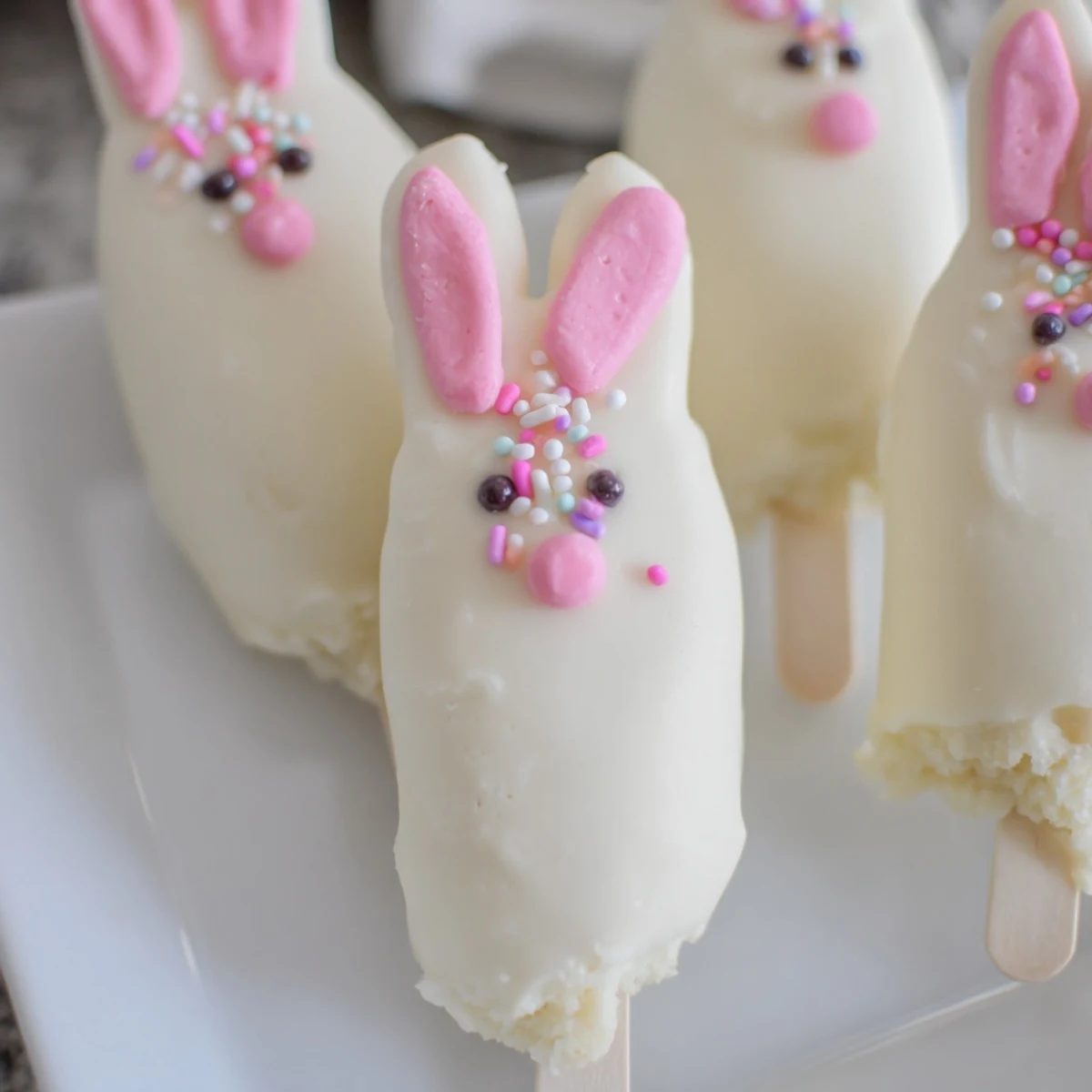 Creamy white chocolate bunny cakesicles decorated with sprinkles for festive Easter treats