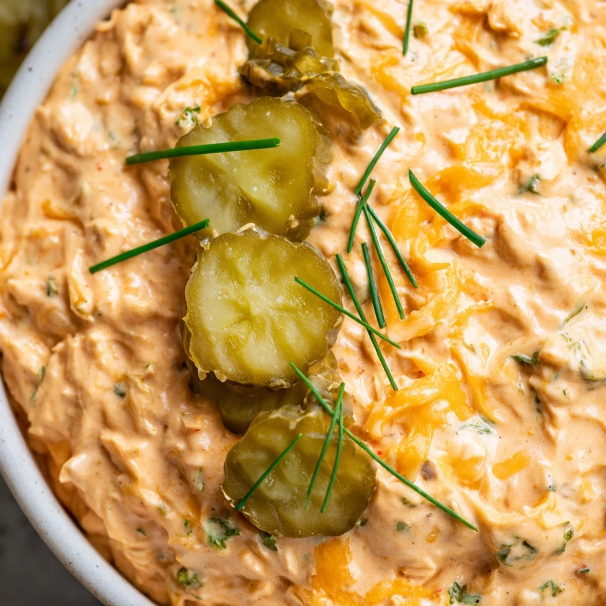 Creamy buffalo pickle dip served in a bowl with crispy chips and fresh vegetable sticks for dipping