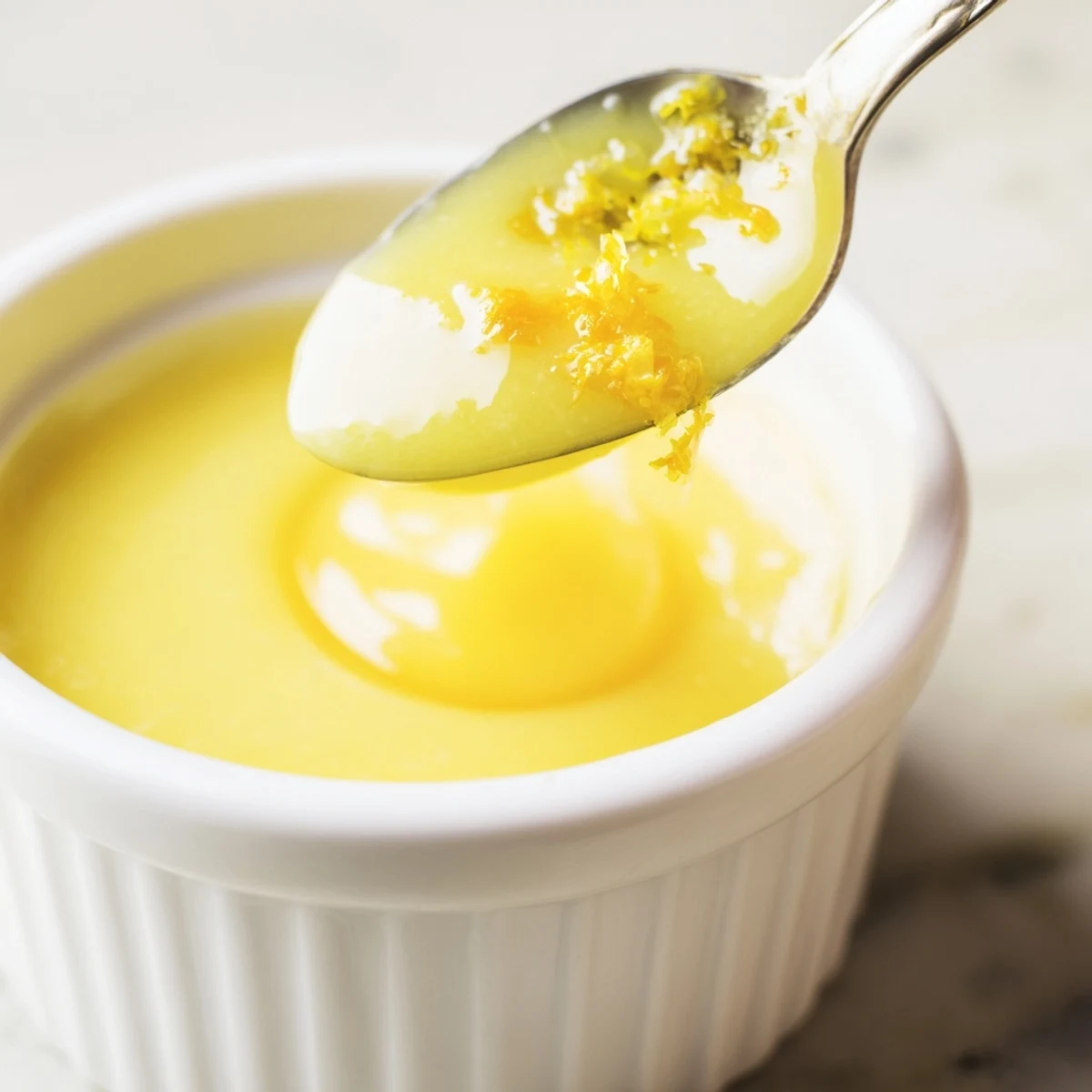 Glossy, bright yellow Lemon Curd Recipe spooned over warm scones