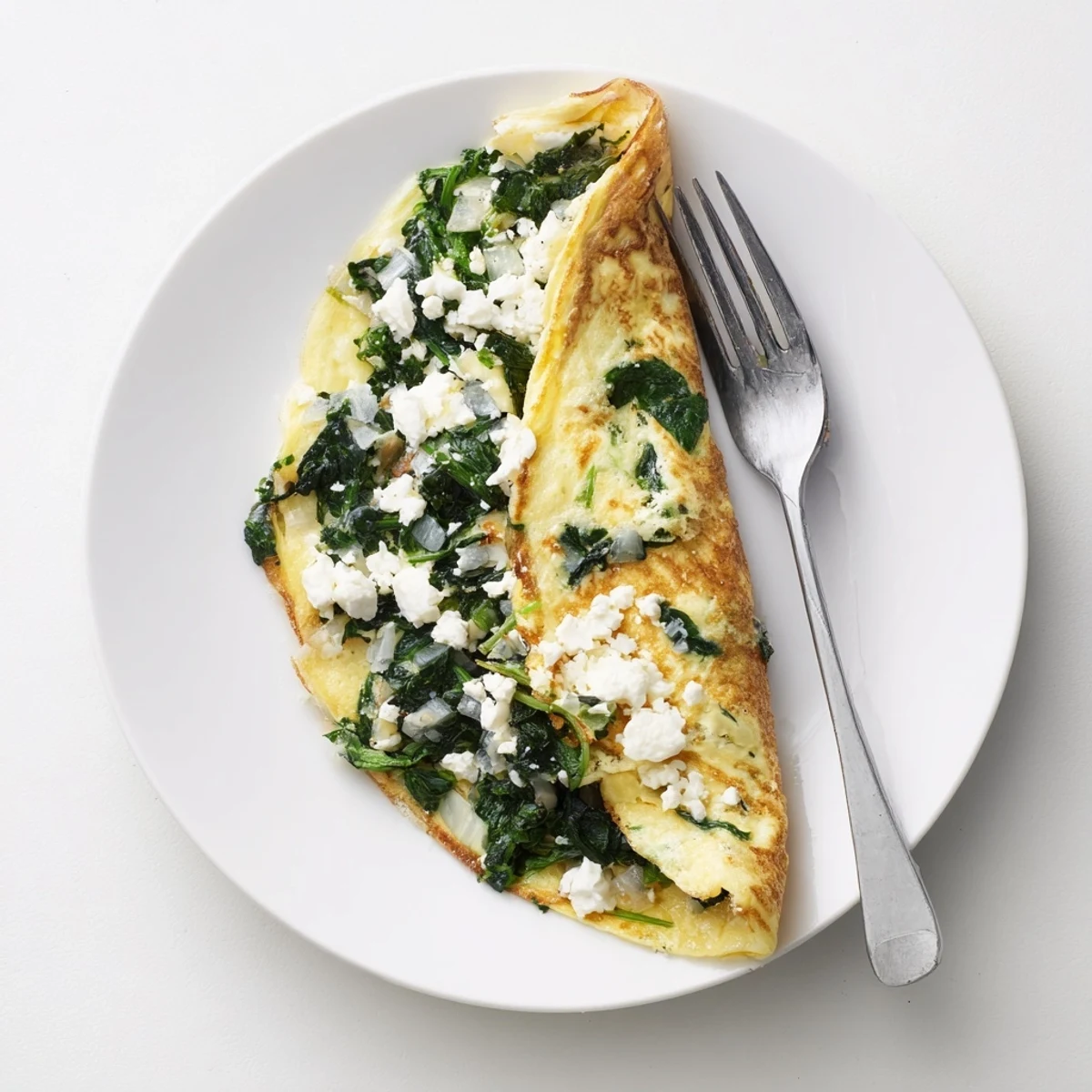 Savory breakfast omelet with tender sautéed spinach and crumbled feta, served hot