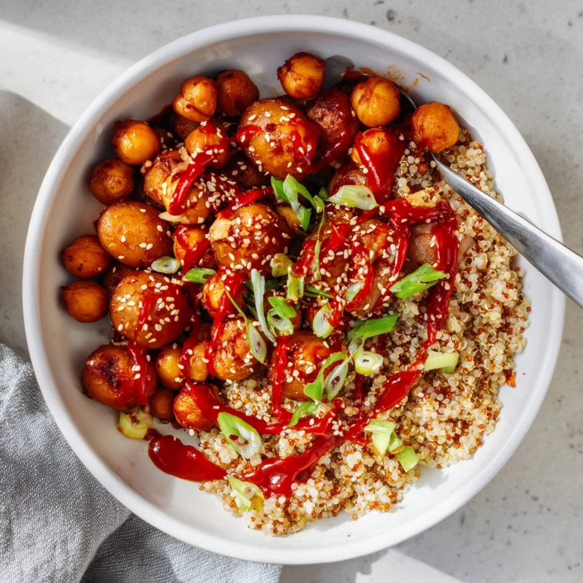 Colorful meal prep bowl with roasted gochujang potatoes chickpeas quinoa topped with fresh spring onions and sesame seeds
