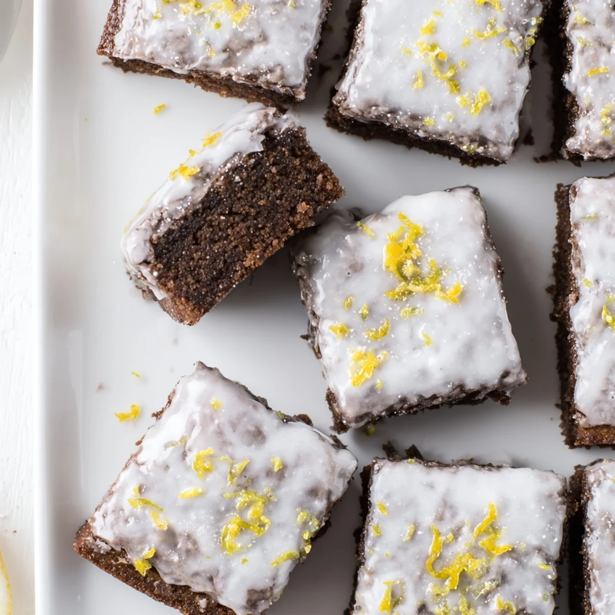 Golden lemon zest brownies with optional white glaze and fresh citrus garnish on a white plate