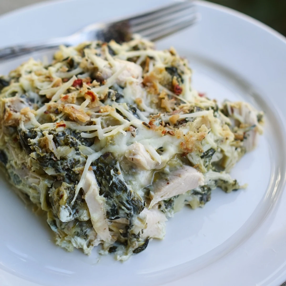 Spoonful of warm Spinach Artichoke Chicken Casserole showing melted cheese pull
