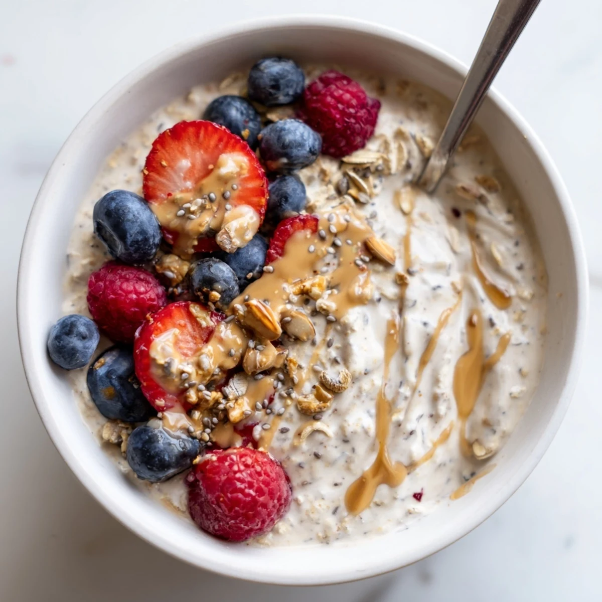 Protein overnight oats in a jar drizzled with nut butter and topped with colorful fruit