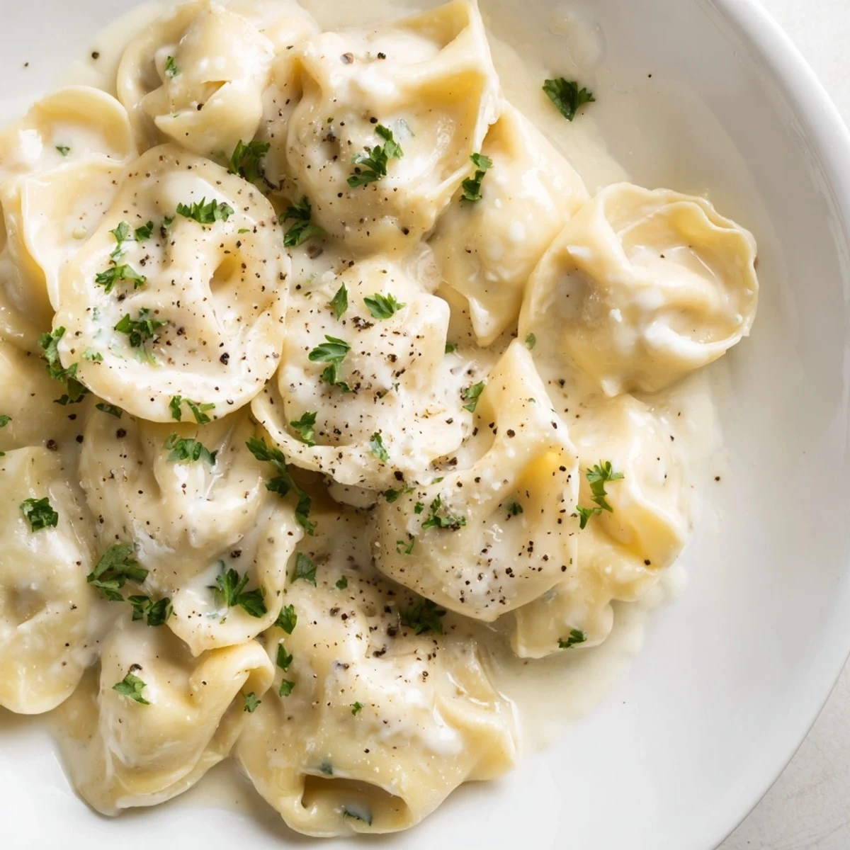 Golden handmade chicken tortellini nestled in a silky butter cream sauce