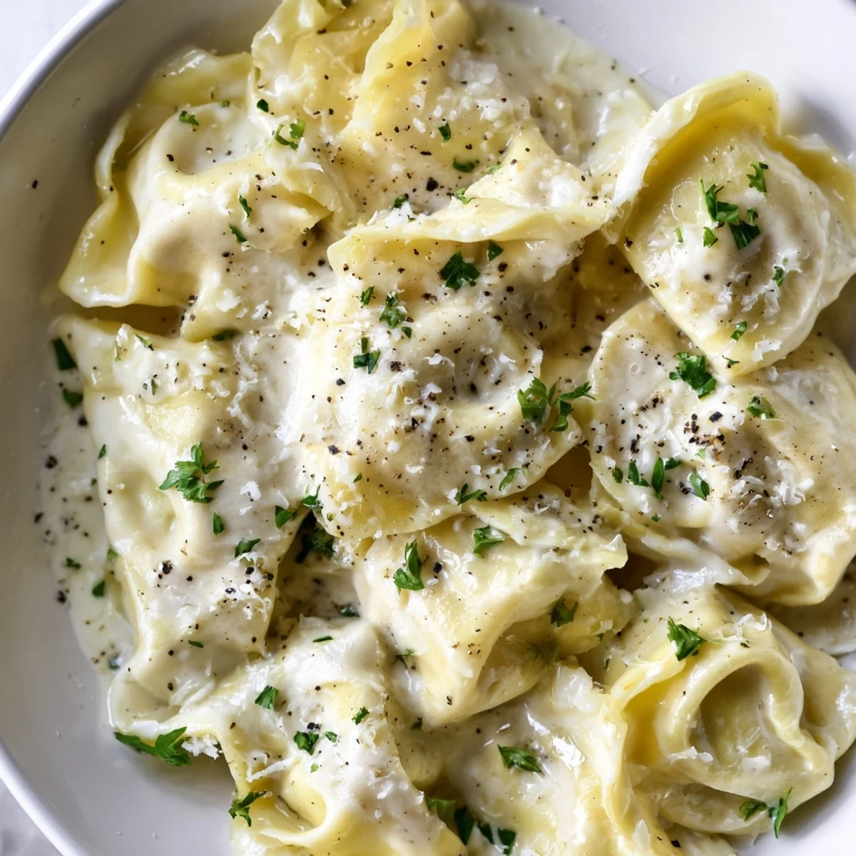 Steaming plate of chicken tortellini tossed in smooth cream sauce sprinkled with parsley