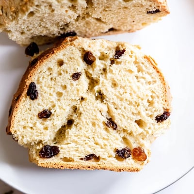 Freshly baked Irish Soda Bread with Currants and Caraway Seeds cooling on a wire rack, its crust lightly dusted with flour.  