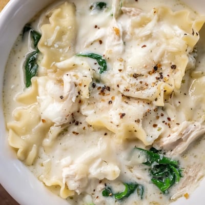 Steaming bowl of white lasagna soup topped with Parmesan and cracked pepper