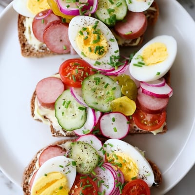 Colorful kanapki arranged on a platter with smoked ham, egg, and crisp cucumber slices